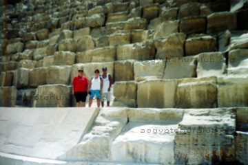 Größenvergleich einer Pyramide in Ägypten beim Ägypten Urlaub indem man ein paar Personen neben den Steinquadern fotografiert.